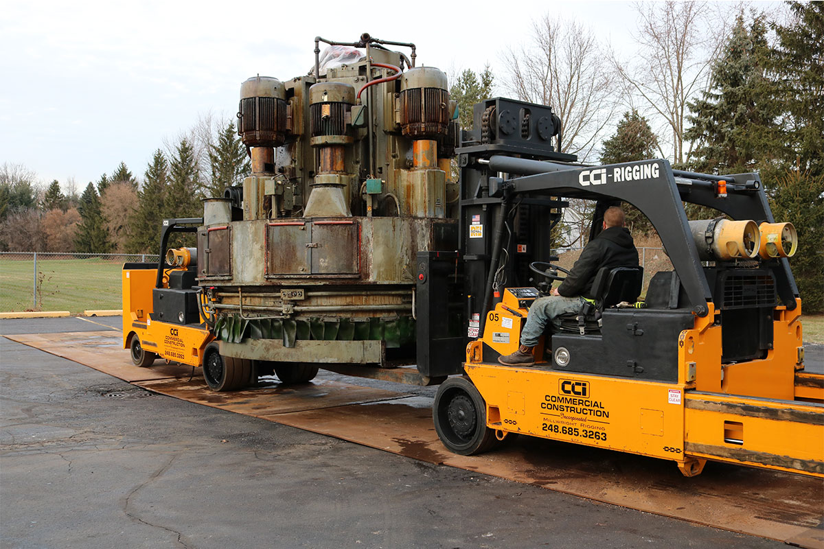 CCI Industrial Constructors - A heavy-duty forklift operated by a worker transporting an industrial machine.