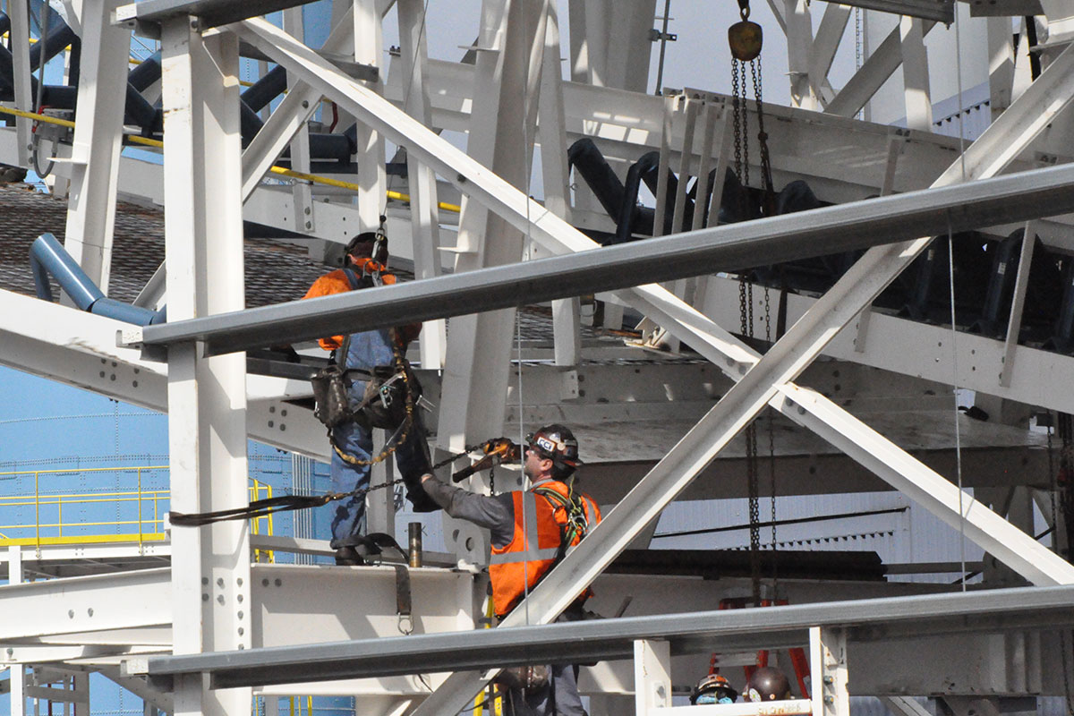 CCI Industrial Constructors - Workers in high-visibility vests and harnesses assembling a steel structure on a construction site.