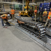 CCI Industrial Constructors - Workers in high-visibility vests operating heavy machinery and performing maintenance in an industrial setting.