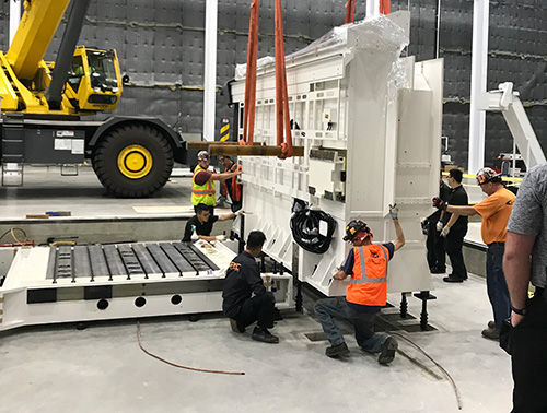 CCI Industrial Constructors - Team of workers collaborating on the installation or maintenance of heavy industrial equipment in a warehouse setting.