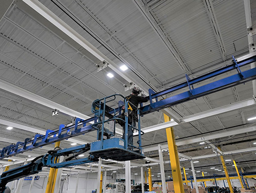 CCI Industrial Constructors - Maintenance worker on a scissor lift performing overhead work in an industrial facility.