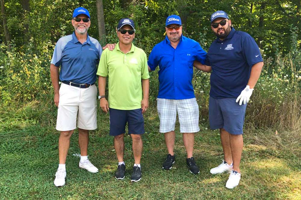 CCI Industrial Constructors - Four smiling men in casual golf attire enjoying a sunny day on the golf course.