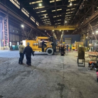 CCI Industrial Constructors - Industrial setting where workers in safety gear are engaged in construction activities with heavy machinery and equipment around.