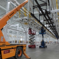 CCI Industrial Constructors - Workers on scissor lifts performing maintenance in a spacious and modern industrial facility.