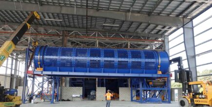 CCI Industrial Constructors - Large industrial blue machinery being installed in a spacious warehouse with workers overseeing the process.