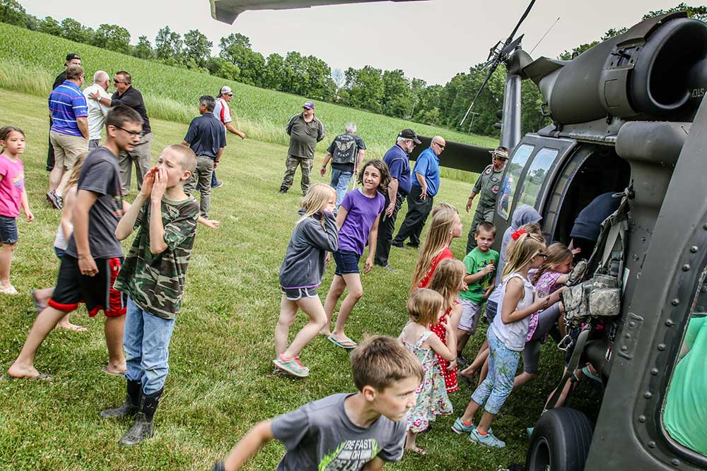 CCI Industrial Constructors - A group of curious children and adults exploring a military helicopter during an outdoor event.