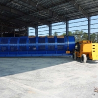 CCI Industrial Constructors - A large industrial blue drum machine mounted on a yellow mobile platform inside a spacious factory building with a steel frame structure under clear skies.