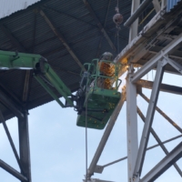 CCI Industrial Constructors - Industrial maintenance in action: a worker operating a cherry picker to weld at height amidst a flurry of sparks.