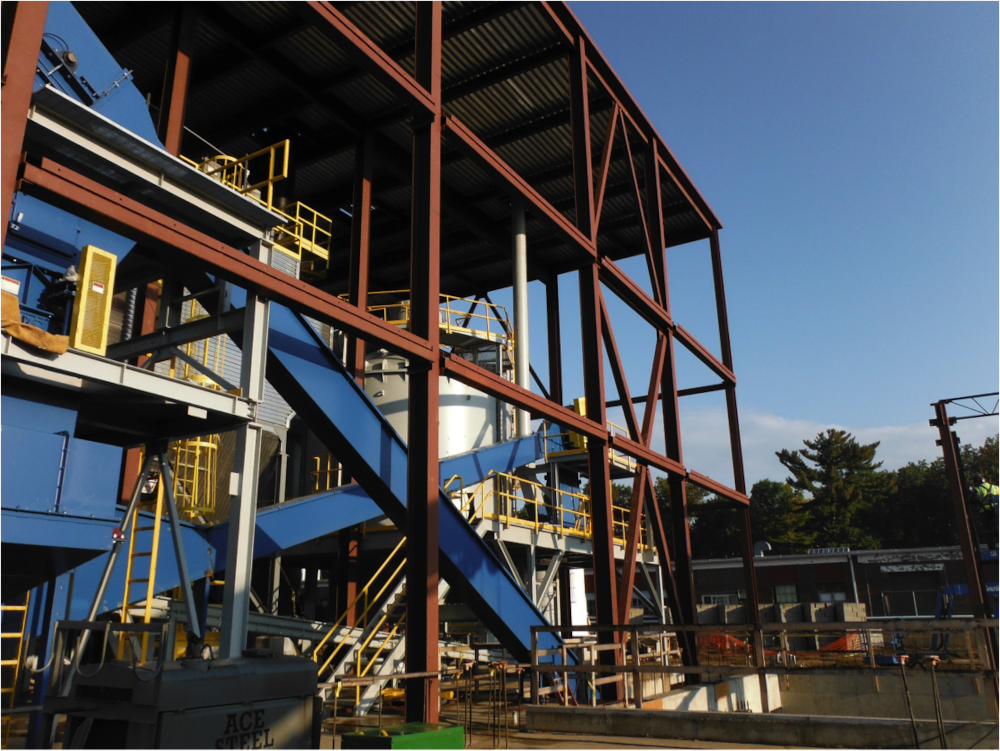 CCI Industrial Constructors - Industrial construction site with steel framework and heavy machinery under a clear blue sky.