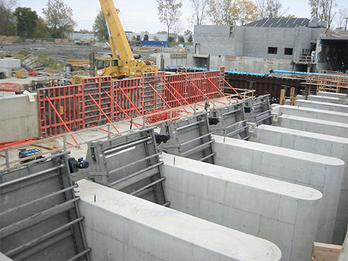 CCI Industrial Constructors - Construction site with concrete foundations in progress, featuring red scaffolding and a yellow crane in the background.