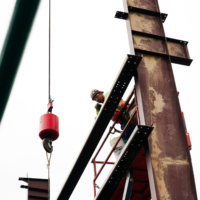 CCI Industrial Constructors - Construction worker securing structural steel beams at a job site.