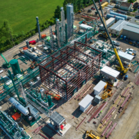 CCI Industrial Constructors - Aerial view of an industrial chemical plant under construction with a network of pipes and steel structures surrounded by green fields.