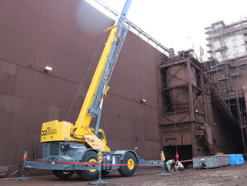 CCI Industrial Constructors - A mobile crane operating next to a large industrial structure with workers overseeing the operations.