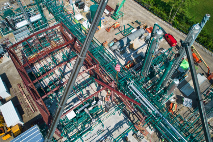 CCI Industrial Constructors - Aerial view of an industrial site with a complex network of green piping and steel structures under construction.